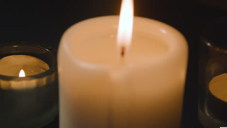 Close-Up-Of-Candles-Burning-On-Table-In-Dark-Room
